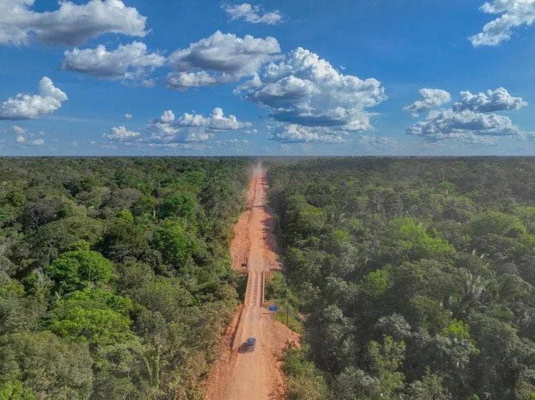 Vista aérea de um trecho da BR-319 cercado pela floresta amazônica, ilustrando o início das obras de pavimentação da rodovia que liga Porto Velho a Manaus.